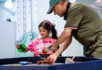 A young visitor and her grown-up playing at one of the plaza interactives