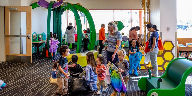 Opening day at Plants and Pollinators — families and kids fill the flower-arch play space
