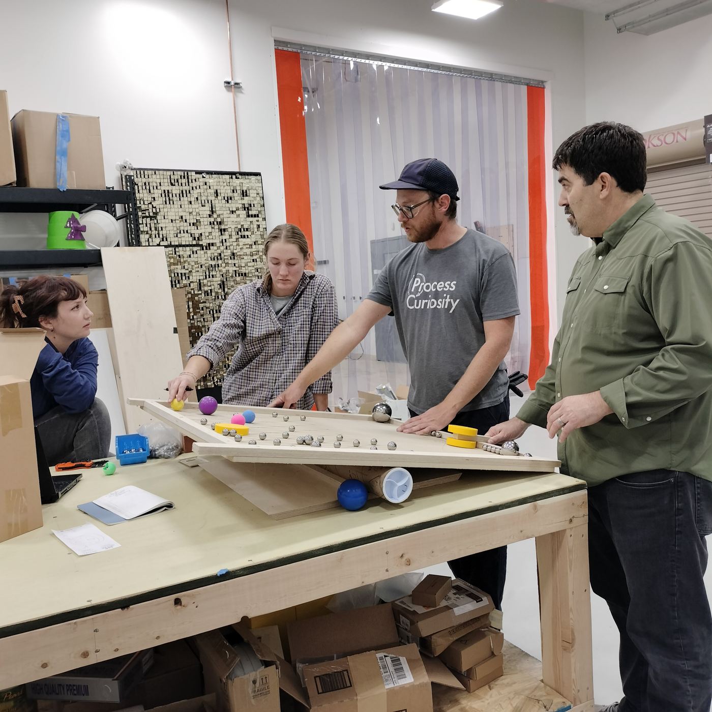The team testing a rolling-ball prototype together at a work table